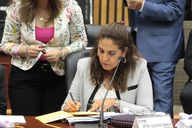 Claudia Zavala Pérez, Consejera Electoral firmando sobre con muestras.