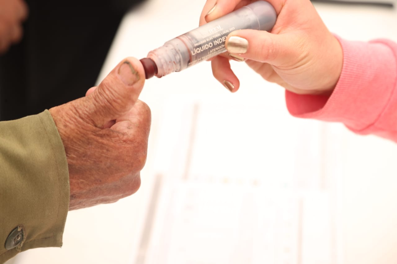 Ciudadano siendo marcado con el liquido indeleble después de ejercer su voto