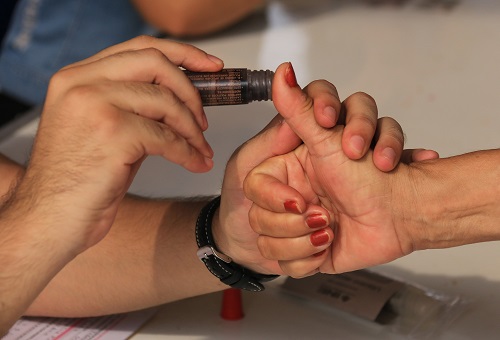 Persona recibiendo liquido indelebre después de ejercer su voto