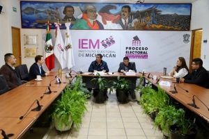 Integrantes del INE e IEM sentados durante firma de plan de trabajo