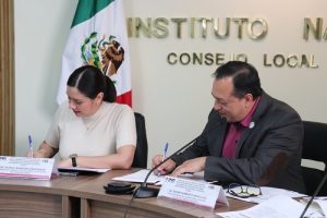 Mujer y hombre de lentes firmando convenio sobre mesa