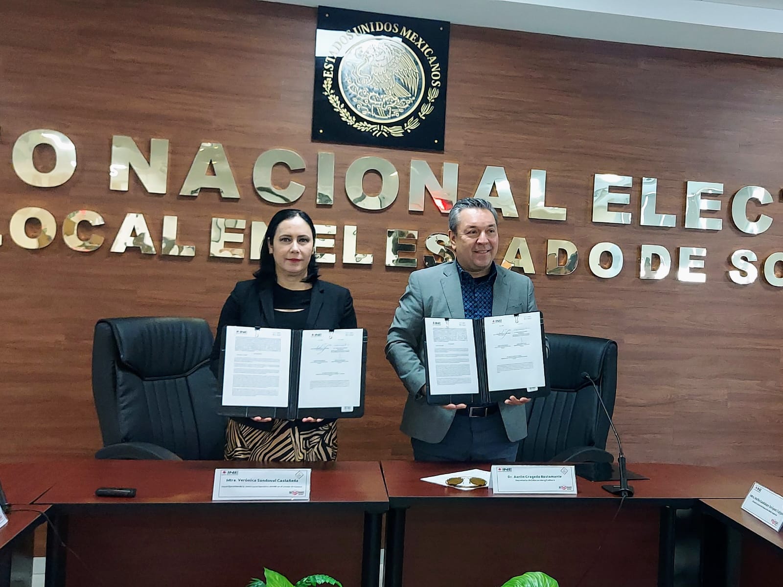 Mujer y hombre posando de pie con convenios firmados
