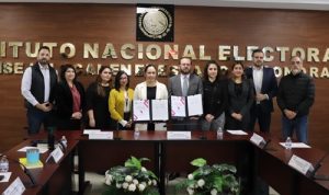 Integrantes del INE e IEE de pie posando con documentos firmados