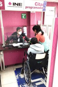 Persona en silla de ruedas siendo atendida en Módulo del INE