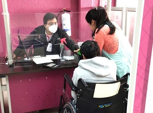 Persona en silla de ruedas siendo atendida en Módulo del INE