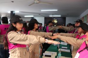 Supervisores Electorales de pie, estirando su brazo derecho