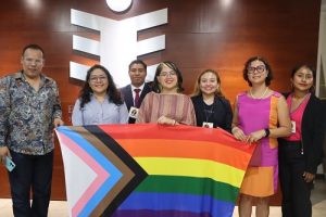 Integrantes de asociación LGTBQ+ posando con bandera del movimiento