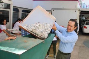 Hombre vaciando caja con credenciales en máquina pulverizadora