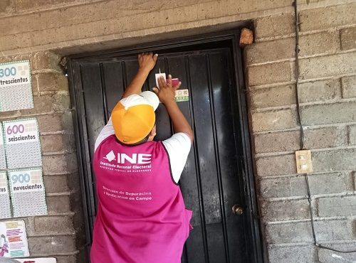 CAE del INE colocando estampa en puerta de domicilio particular