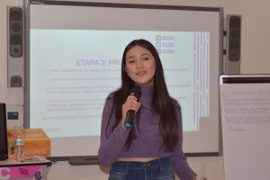 Alumna de la UNISON participando en conversatorio con micrófono en mano