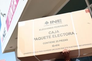 Caja de material electoral siendo cargada por integrante del INE