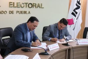 Vocal del INE y representante de asociación firmando convenio