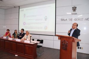 Vocal del INE Jalisco en atril, a su lado panelistas sentados