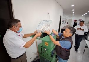 Dos integrantes del INE vaciando caja con credenciales a máquina pulverizadora