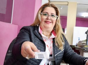 Integrante del INE extendiendo el brazo con una credencial en la mano