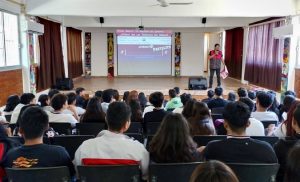 Auditorio con jóvenes estudiantes sentados mientras integrantes del INE presentan
