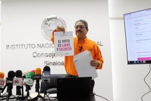 Vocal del INE en Sinaloa sosteniendo una hoja donde se lee "El voto es libre y secreto"