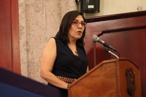 La Consejera Electoral hablando en podio con micrófono