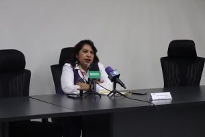 Mujeres sentada hablando a dos micrófonos frente a ella