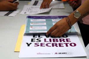 Manos de mujer sosteniendo boleta electoral sobre mesa