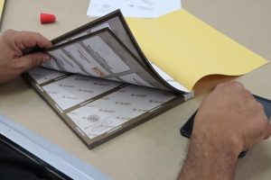Manos revisando boletas electorales sobre mesa