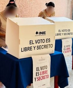 Dos personas en prisión preventiva ejerciendo su voto frente a dos urnas