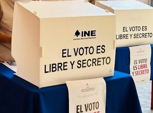 Dos personas en prisión preventiva ejerciendo su voto frente a dos urnas