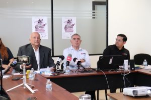 Tres hombres vestidos de manera formal sentados en junta de trabajo