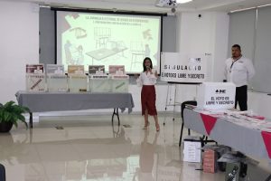 Mujer de pie con micrófono presentando material para simulacro electoral