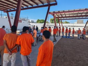 Hombres en prisión preventiva haciendo fila para votar en patio de prisión