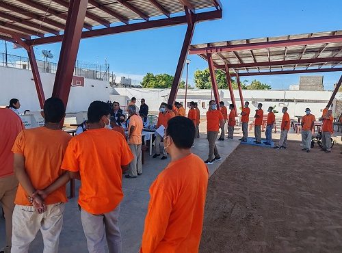 Hombres en prisión preventiva haciendo fila para votar en patio de prisión