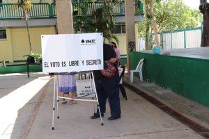 Mujer votando en casilla instalada en patio de escuela
