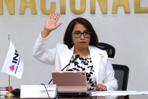 Mujer con lentes sentada levantando su mano derecha