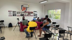 personas sentadas frente a una mesa con una cámara y personal del INE en Quintana Roo