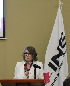 Mujer de lentes de pie en atril con micrófono