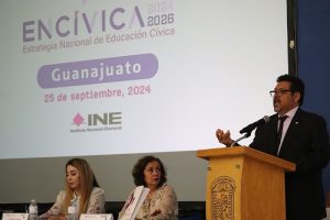 Hombre de lentes hablando en atril con micrófono, de fondo integrantes del presidio sentados