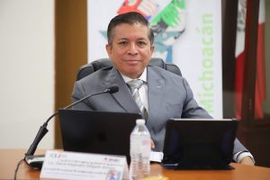 Hombre trajeado, sentado detrás de escritorio con laptop