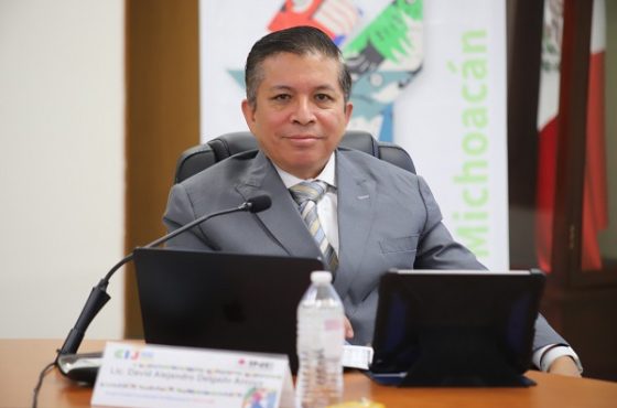 Hombre trajeado, sentado detrás de escritorio con laptop