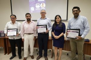Presentadores y organizadores de sesión pública posando con sus reconocimientos