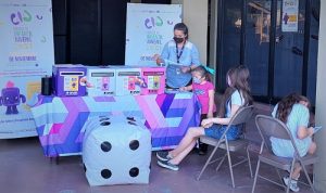 niñas sentadas frente a una mesa con urnas de colores