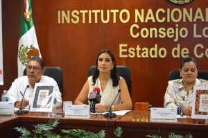 tres mujeres sentadas frente a una mesa con micrófonos