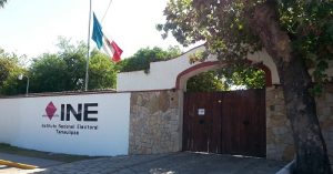 entrada de una casa con un marco y en una pared blanca el letrero del INE