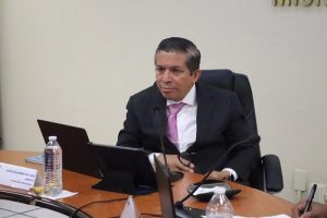 hombre de traje negro sentado frente a una computadora