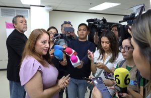 mujer de pie frente a personas con micrófonos y cámaras de video