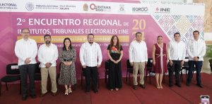 varias personas de pie frente a una lona color rosa