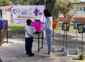 niño en un parque metiendo en una caja rosa una hoja