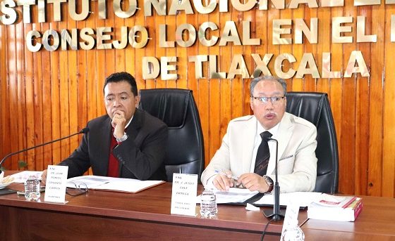 dos hombres sentados atrás de una mesa de madera con micrófono