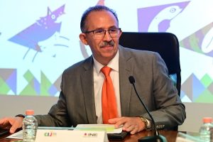 Hombre de lentes sentado frente a un micrófono color negro