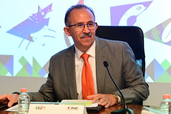 Hombre de lentes sentado frente a un micrófono color negro