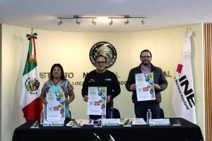 tres personas de pie mostrando un cartel de la Consulta Infantil 2024